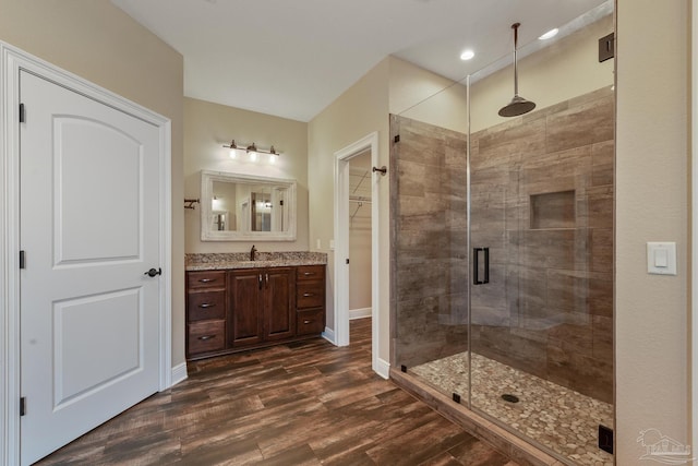 bathroom featuring wood-type flooring, a shower with shower door, and vanity