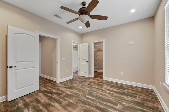 unfurnished bedroom with dark wood-type flooring, ceiling fan, and a spacious closet