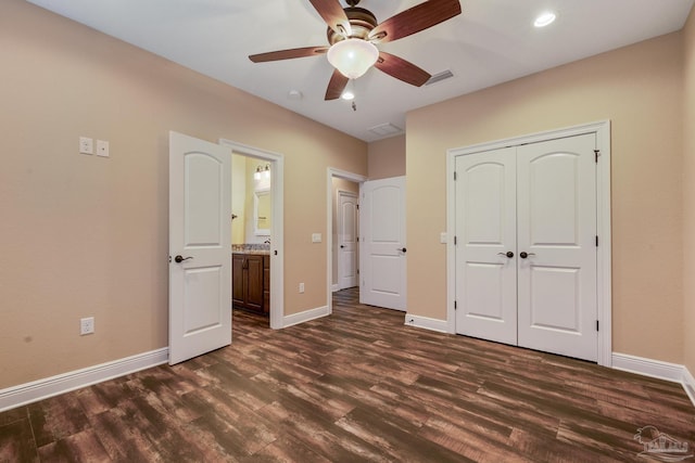 unfurnished bedroom featuring ensuite bathroom, dark hardwood / wood-style floors, ceiling fan, and a closet