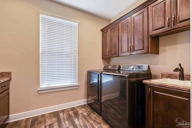 washroom with cabinets, washing machine and dryer, sink, and dark hardwood / wood-style flooring