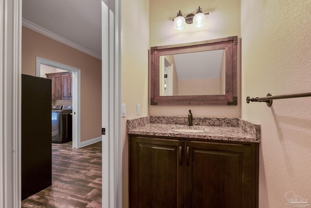 bathroom with crown molding, washing machine and clothes dryer, wood-type flooring, and vanity