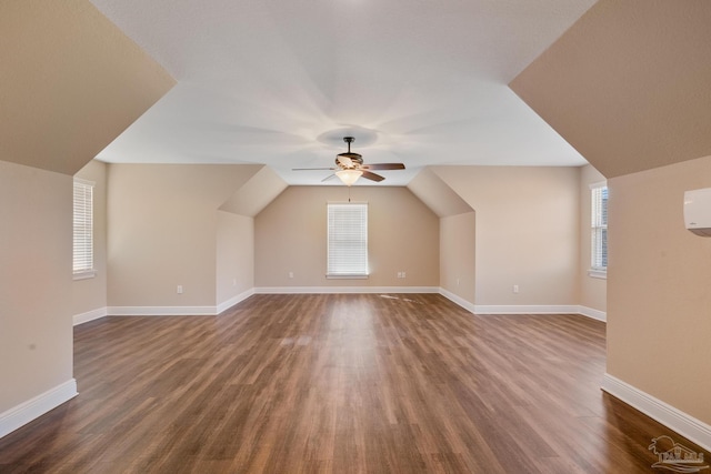 additional living space featuring vaulted ceiling, plenty of natural light, and dark wood-type flooring