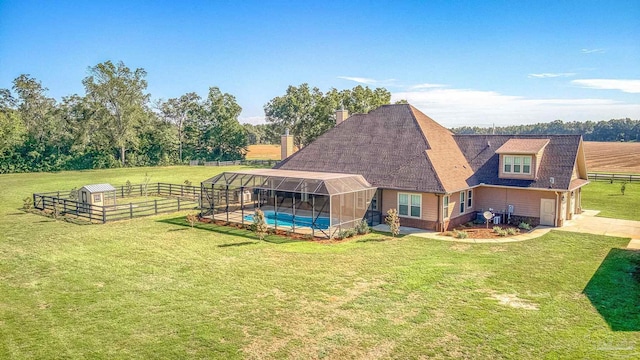 rear view of house with a yard, a lanai, a fenced in pool, and a rural view