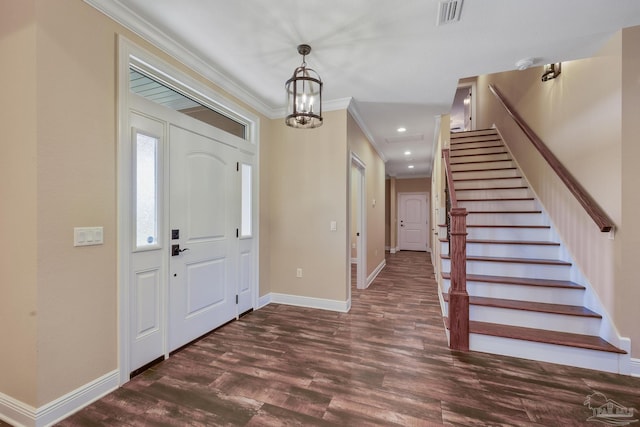 foyer entrance with an inviting chandelier, ornamental molding, and dark hardwood / wood-style floors