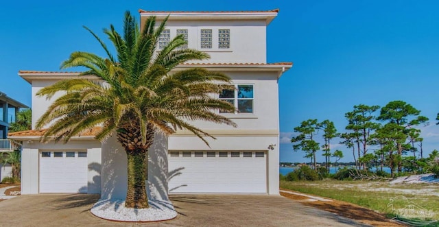 mediterranean / spanish home featuring an attached garage, driveway, and stucco siding