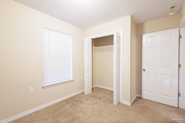 unfurnished bedroom featuring light colored carpet, a textured ceiling, and a closet