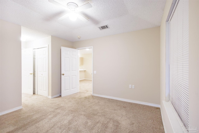 unfurnished bedroom featuring ceiling fan, a textured ceiling, and light carpet