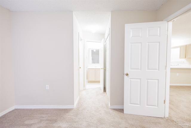 corridor with a textured ceiling and light colored carpet