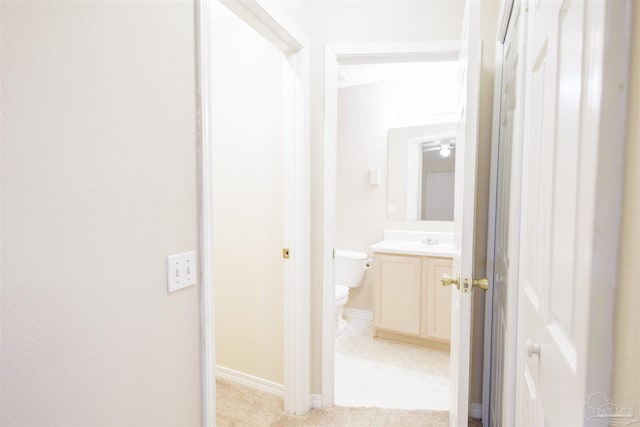 corridor featuring light colored carpet and sink