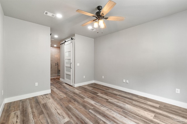 277 Seamarge Ln, Pensacola, FL 32507 - empty room featuring a barn door, ceiling fan, wood finished floors, baseboards, and recessed lighting