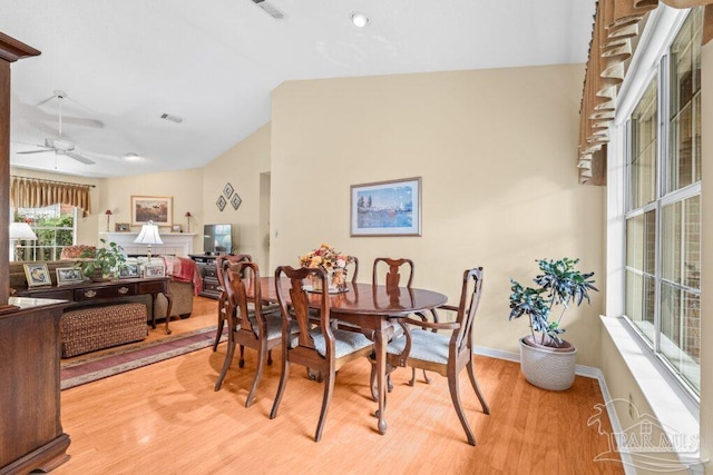 dining room with ceiling fan, vaulted ceiling, and light hardwood / wood-style flooring