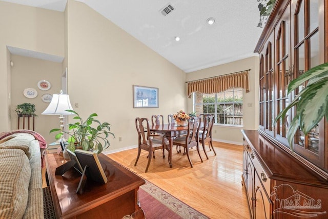 dining space featuring hardwood / wood-style flooring and high vaulted ceiling