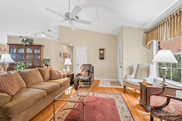 living room featuring ceiling fan, lofted ceiling, light hardwood / wood-style flooring, and a textured ceiling