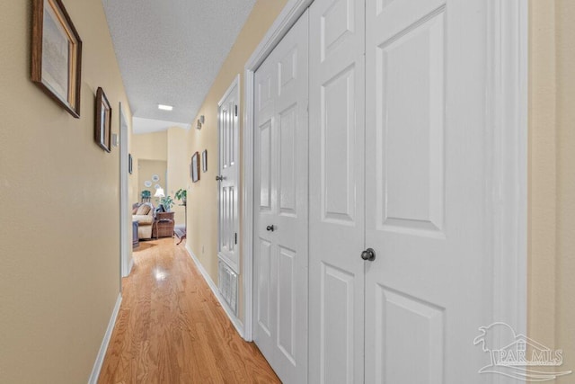 corridor featuring a textured ceiling and light hardwood / wood-style floors