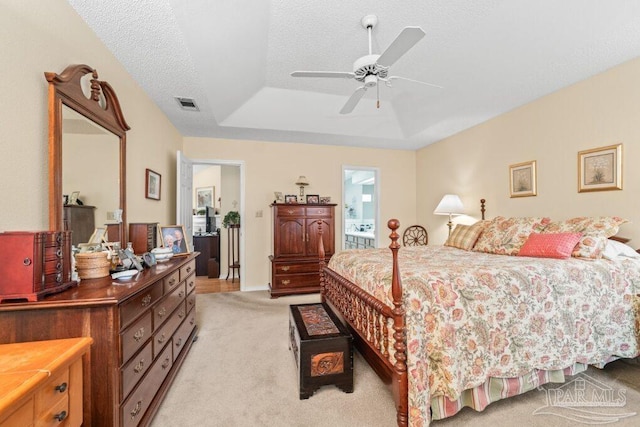 carpeted bedroom with ceiling fan, a textured ceiling, and a tray ceiling