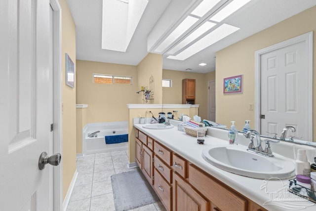 bathroom with vanity, a tub to relax in, a skylight, and tile patterned floors