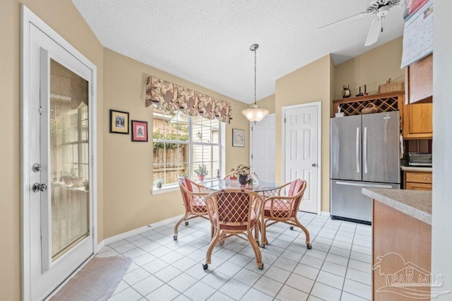 dining area with ceiling fan, lofted ceiling, light tile patterned floors, and a textured ceiling