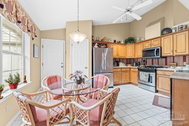 kitchen featuring light tile patterned floors, ceiling fan, appliances with stainless steel finishes, decorative light fixtures, and vaulted ceiling