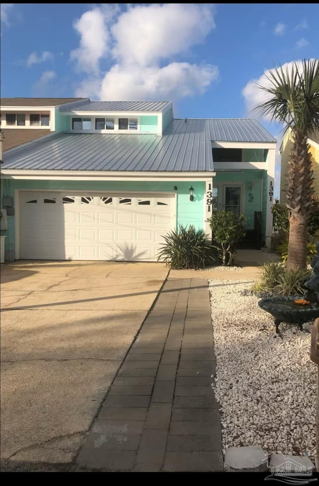 view of front of house with metal roof, concrete driveway, and a garage