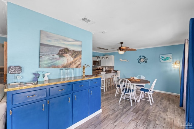 kitchen with visible vents, wood finished floors, blue cabinetry, and a sink