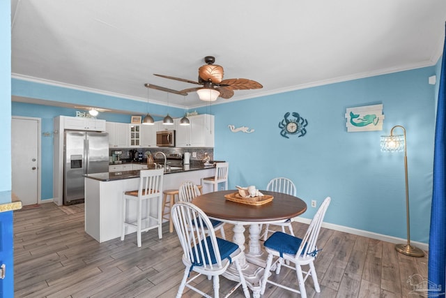 dining space with baseboards, wood finished floors, a ceiling fan, and ornamental molding