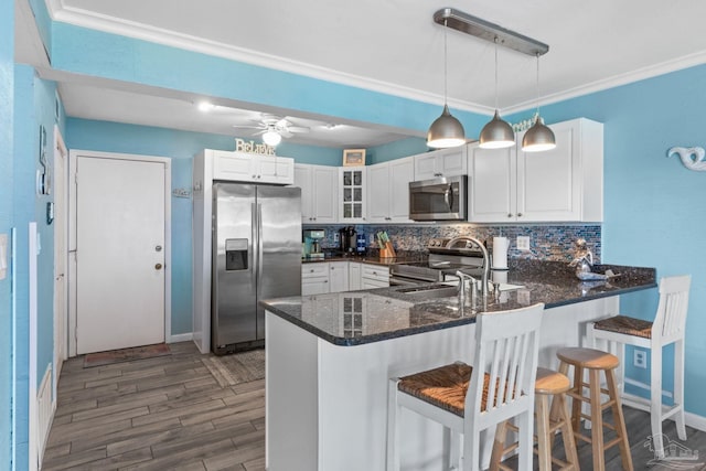 kitchen featuring backsplash, stainless steel appliances, a peninsula, and white cabinetry