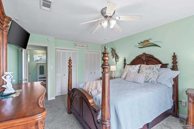 carpeted bedroom with a ceiling fan, two closets, visible vents, baseboards, and a textured ceiling