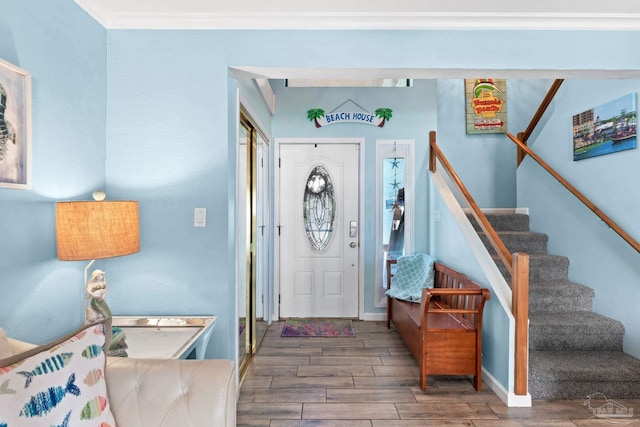 entryway with ornamental molding, stairway, wood finish floors, and baseboards