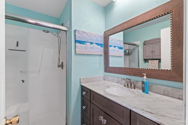 full bath with vanity, a stall shower, and a textured wall