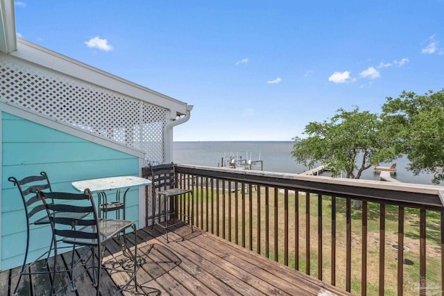 wooden terrace featuring a water view and a yard