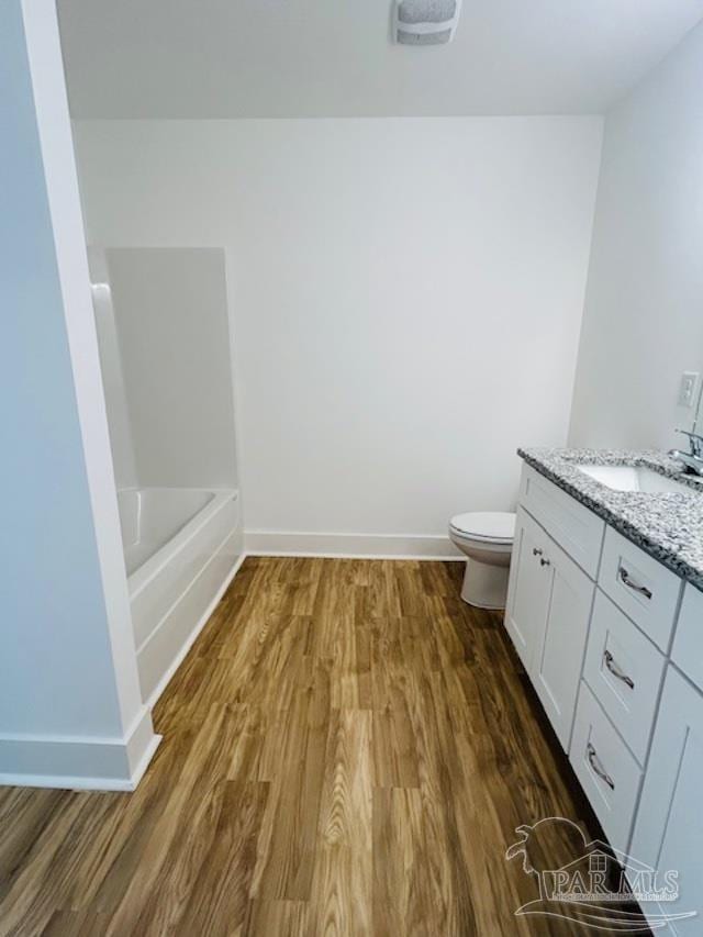 bathroom with vanity, hardwood / wood-style flooring, toilet, and a bathtub