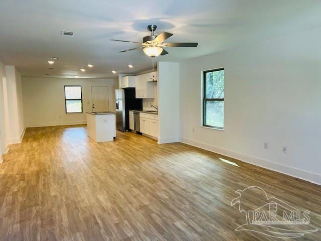 unfurnished living room with a wealth of natural light, sink, ceiling fan, and light wood-type flooring