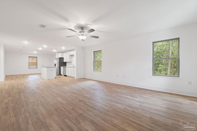 unfurnished living room with a wealth of natural light, ceiling fan, and light hardwood / wood-style floors