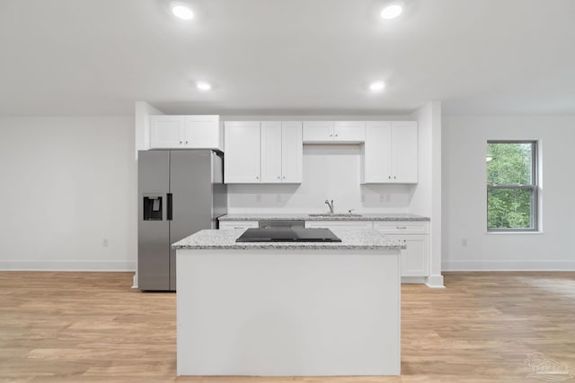 kitchen featuring white cabinets, stainless steel fridge, light hardwood / wood-style flooring, and sink