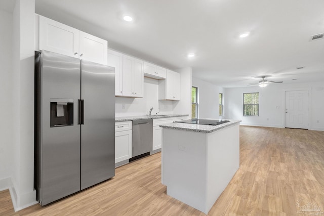 kitchen featuring appliances with stainless steel finishes, light hardwood / wood-style floors, white cabinetry, and a kitchen island