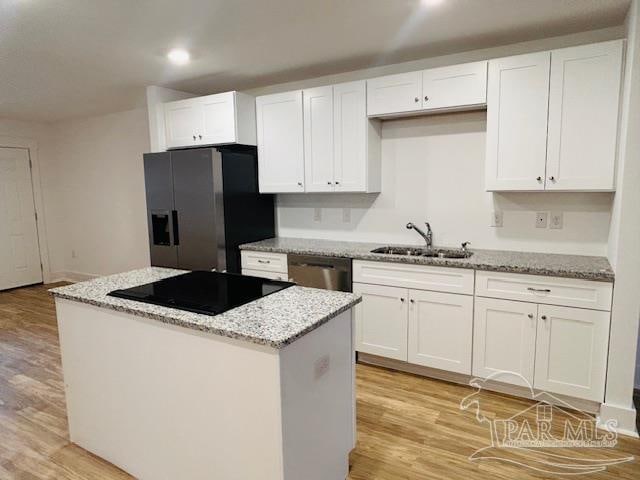 kitchen featuring white cabinets, sink, a center island, light wood-type flooring, and stainless steel appliances