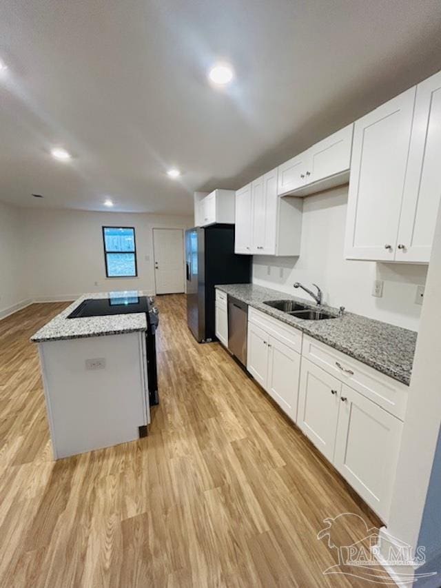 kitchen with sink, appliances with stainless steel finishes, stone countertops, white cabinets, and light wood-type flooring