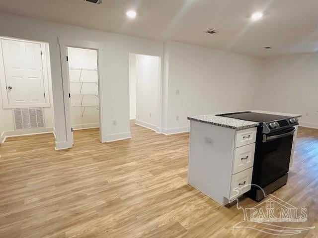 kitchen with black electric range, a center island, white cabinets, and light wood-type flooring