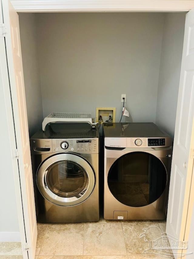 clothes washing area featuring laundry area, tile patterned flooring, and washing machine and clothes dryer