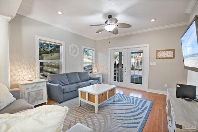 living room with ornate columns, ornamental molding, ceiling fan, light wood-type flooring, and french doors