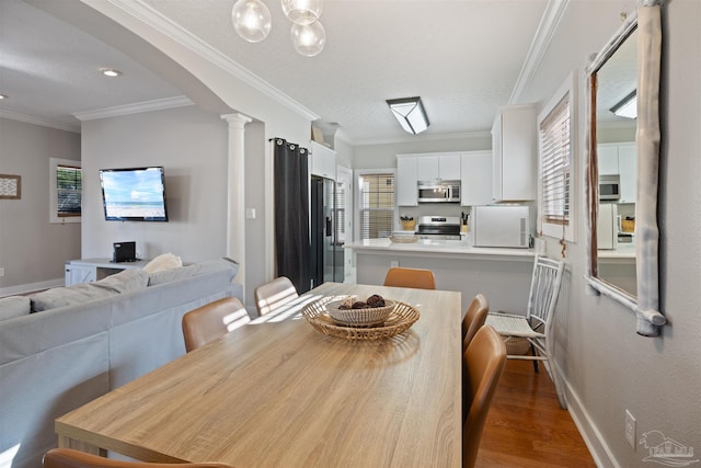 dining space with dark hardwood / wood-style flooring, ornamental molding, and ornate columns