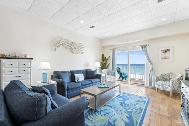 living room featuring a paneled ceiling, a water view, and visible vents