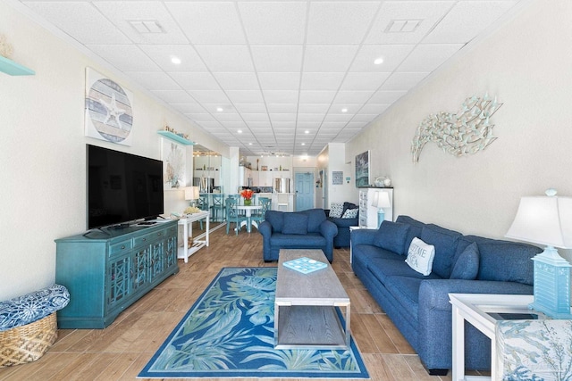 living area featuring light wood-style floors, a paneled ceiling, and recessed lighting