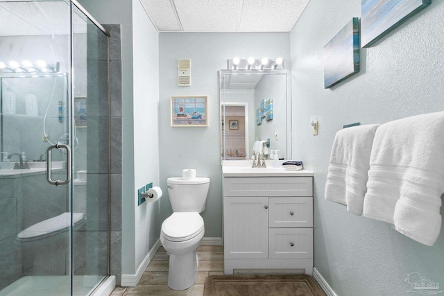 bathroom featuring toilet, a shower stall, baseboards, and vanity