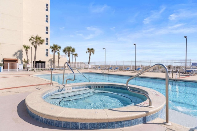 community pool featuring a hot tub and fence