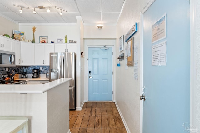 kitchen featuring a peninsula, white cabinetry, light countertops, appliances with stainless steel finishes, and backsplash