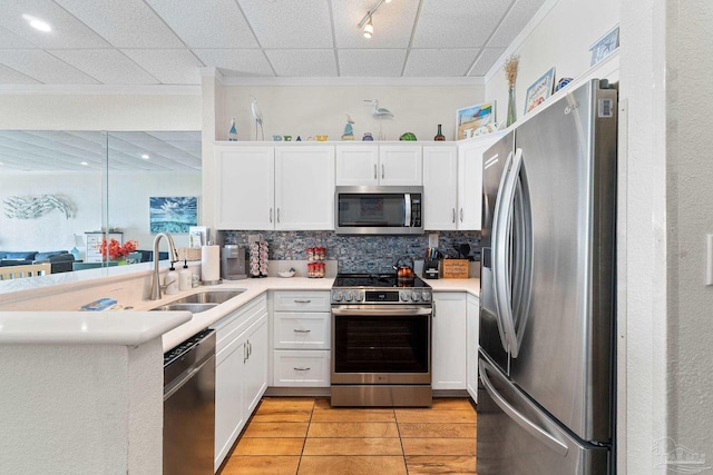 kitchen featuring stainless steel appliances, a peninsula, light countertops, and white cabinetry