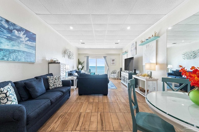 living room with wood finished floors, a paneled ceiling, and crown molding