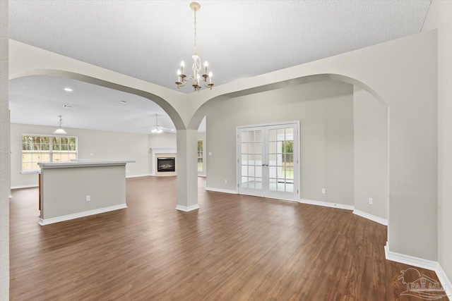 unfurnished living room featuring dark hardwood / wood-style floors, ceiling fan with notable chandelier, and a textured ceiling