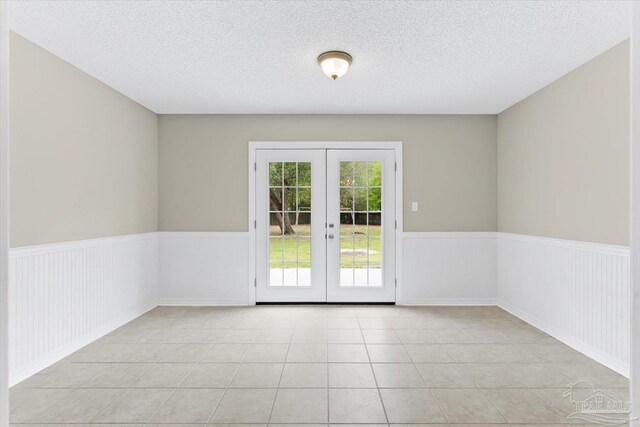 entryway featuring light tile patterned floors, french doors, and a textured ceiling